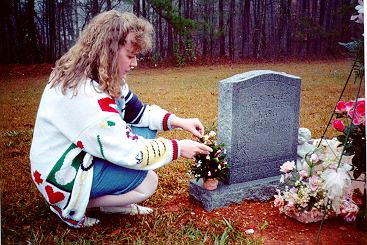 [Patricia decorating a miniature Christmas tree at Mary's grave]